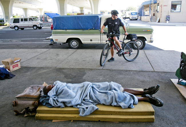 In this Sept. 4, 2014, file photo, Boise, Idaho, bike police officer Andy Johnson stops in front of an area known for homeless people. [File Photo: Idaho Statesman via AP/Kyle Greene]