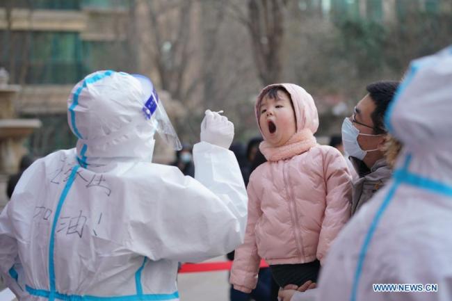 Zdravotnický pracovník odebírá vzorek výtěru od dívky na sídlišti ve čtvrti Qiaoxi v Shijiazhuang, hlavním městě severočínské provincie Hebei, 6. ledna 2021. Shijiazhuang začal ve středu provádět testy nukleových kyselin pokrývající všechny občany. (Xinhua / Mu Yu)