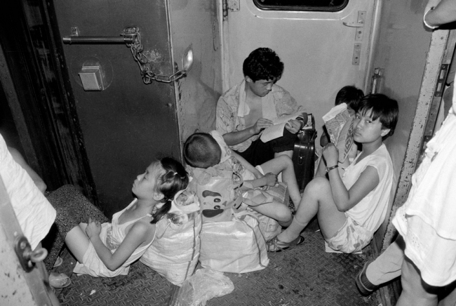 V roce 1988 ve vlaku K264 železniční linky mezi Pekingem a Baotou (Pao-tchou) odpočívali cestující bez sedadel v uličce. V 70. a 80. letech vedla nedostatečná přepravní kapacita k přeplněnosti vlaků. Fotografie: Yuan Ruilung (Jüan Žuej-lung) pro deník China Daily