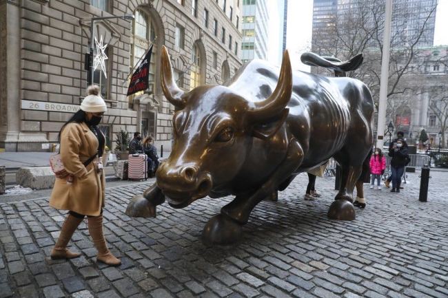 Žena prochází kolem sochy býka na Wall Street v New Yorku ve Spojených státech, 21. prosince 2020. (Xinhua / Wang Ying)