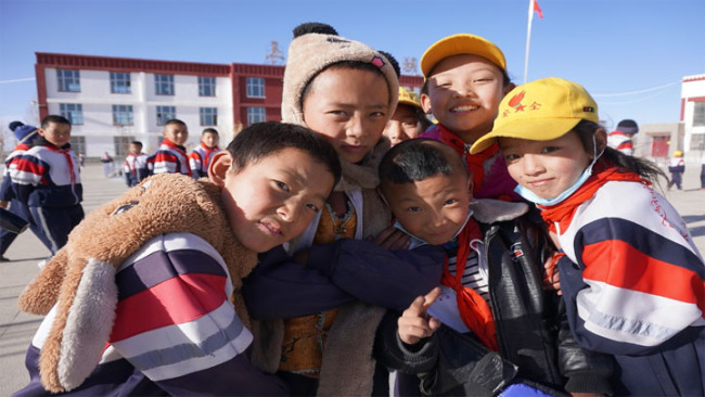 Snímek: Skupina studentů ze základní školy s názvem Changjiangyuan Minzu (Čchang-ťiang-jüan Min-cu) pózuje pro fotografii. / CGTN
