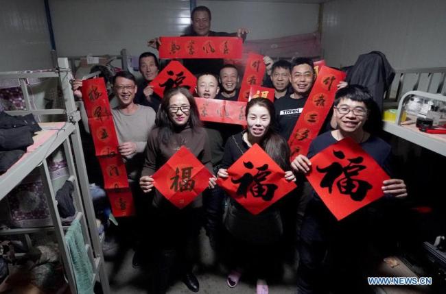 Zaměstnanci stavebního projektu na nádraží Fengtai (Feng-tchaj) pózují pro společnou fotografii na ubytovně v Pekingu, hlavním městě Číny, 11. února 2021. Letošní Jarní svátek připadá na pátek. (Xinhua / Wang Yuguo)