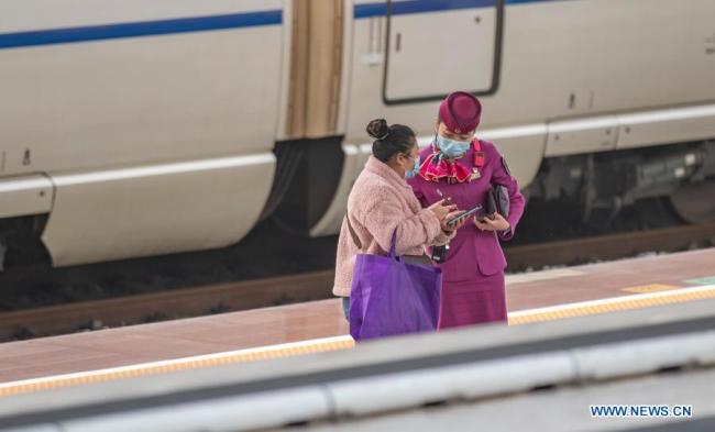 Zaměstnanec odpovídá na otázky cestujícího na nástupišti na nádraží Chongqing-sever (Čchung-čching) ve městě Chongqing v jihozápadní Číně, 17. února 2021. Ve středu je poslední den Jarních svátků. Železniční nádraží vstoupila do špičky vracejících se cestujících a železniční oddělení Chongqing podniklo opatření, aby cestující mohli cestovat snadno a bezpečně. (Xinhua / Huang Wei)