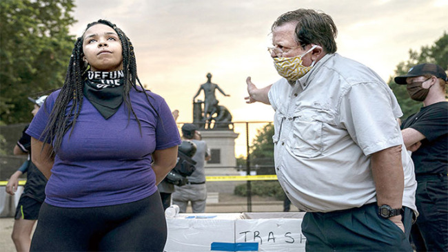 snímek: 25. června 2020 v Lincoln Parku ve Washingtonu debatuje 26letá Anais (vlevo) s mužem o osudu Památníku osvobození Lincolna za sebou. Anais se zasazovala o odstranění památníku, zatímco muž se zasazoval o zachování památníku. Foto: Evelyn Hockstein