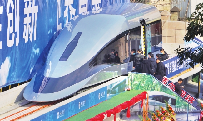 Lidé si prohlíží prototyp doma vyvinutého vlaku založeného na supravodivé technologii uplatňujícího princip vznášení nad kolejemi – maglev, který ve středu v provincii Sinchuan na jihozápadě Číny sjel z výrobní linky. Vlak přezdívaný „super-kulka maglev“ má maximální rychlost 620 km/h. Photo: VCG