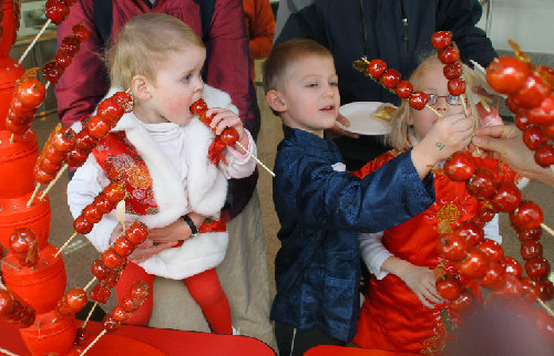 Tres alumnos de la Escuela Internacional de Tianjin prueban tanghulu, dulce típico de China hecho de acerolas.