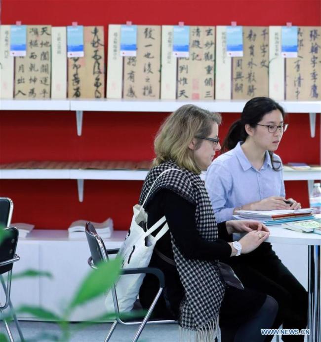 Une visiteuse discute avec des exposants dans le pavillon chinois de la 69e Foire du livre de Francfort, en Allemagne, le 11 octobre 2017.