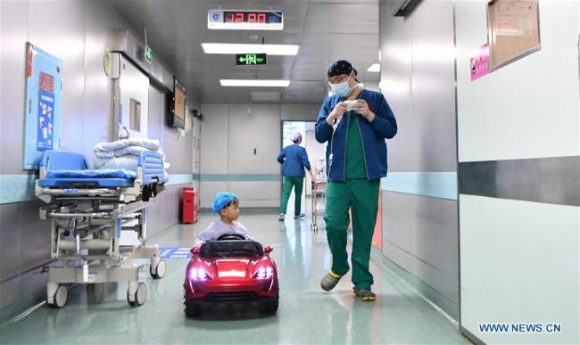 Un enfant à bord d'une petite voiture à l'Hôpital des enfants du Hunan, à Changsha, capitale de la province chinoise du Hunan (centre), le 11 janvier 2018. Depuis octobre 2017, l'hôpital permet aux enfants de "conduire" des petites voitures pour se rendre au bloc afin d'atténuer leur nervosité avant une opération. (Photo : Xue Yuge)