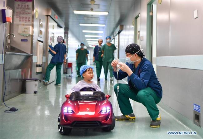 Un enfant à bord d'une petite voiture à l'Hôpital des enfants du Hunan, à Changsha, capitale de la province chinoise du Hunan (centre), le 11 janvier 2018. Depuis octobre 2017, l'hôpital permet aux enfants de "conduire" des petites voitures pour se rendre au bloc afin d'atténuer leur nervosité avant une opération. (Photo : Xue Yuge)