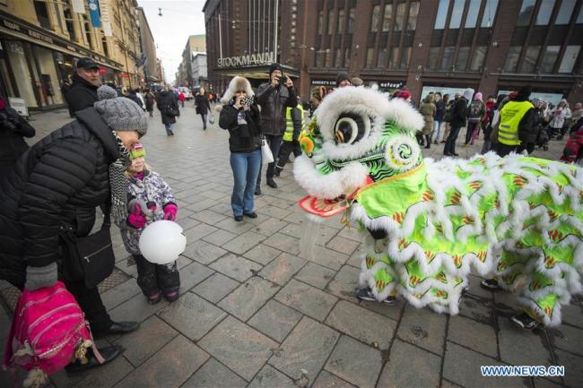 Des Finlandais regardent une danse du lion à Helsinki en Finlande, le 15 février 2018. La 12e "Joyeuse fête du Printemps - Foire du temple à Helsinki" a été organisée à Helsinki pour célébrer le Nouvel An lunaire chinois. (Photo : Matti Matikainen)