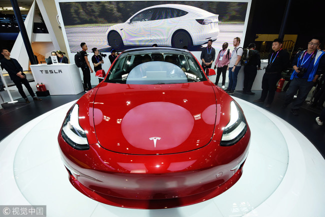 Des visiteurs regardent une Tesla Model 3 lors du salon Auto China 2018, le 25 avril 2018 à Beijing.