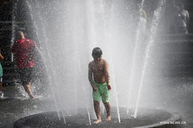 Un jeune garçon se rafraîchit dans une fontaine à New York aux Etats-Unis, le 2 juillet 2018. La température a atteint jusqu'à 35 degrés lundi dans la ville américaine. (Photo : Wang Ying)