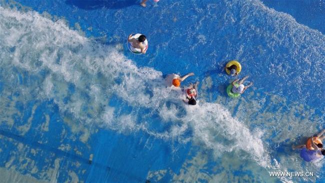 Des touristes jouent dans des vagues artificielles, dans un parc aquatique de Yangzhou, ville de la province chinoise du Jiangsu (est), le 17 juillet 2018. Les gens aiment jouir de la fraîcheur de l'eau, alors que commencent les jours les plus chauds de l'été. (Photo : Meng Delong)