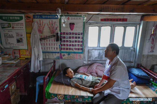 Le docteur Li Shaoyou traite un jeune patient sur sa « clinique flottante » dans le village de Mudundao du canton de Bancheng, au comté de Sihong, dans la province du Jiangsu (est), le 27 juin 2018. M. Li offre des services médicaux aux pêcheurs du lac Hongze depuis plus de trois décennies. Un grand nombre de praticiens médicaux sont actifs dans les zones rurales chinoises, où les soins de santé sont encore sous-développés. Pratiquant dans des conditions de travail défavorables, ils portent en eux l'esprit humanitaire et se sont consacrés à la santé des citoyens ruraux. La Chine a marqué sa première Journée des travailleurs médicaux le 19 août 2018.