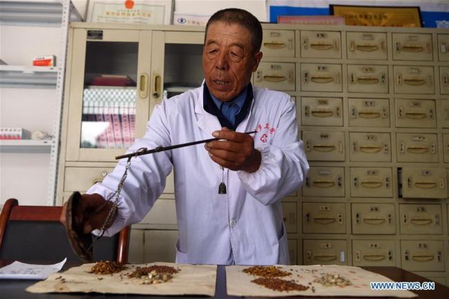 Le docteur Wang Guilin distribue des herbes selon une ordonnance de médecine traditionnelle chinoise dans le village de Yueming, dans le comté de Mawu à Pingliang, dans la province du Gansu (nord-ouest), le 15 août 2018. M. Wang travaille dans ce village depuis 1968. Un grand nombre de praticiens médicaux sont actifs dans les zones rurales chinoises, où les soins de santé sont encore sous-développés. Pratiquant dans des conditions de travail défavorables, ils portent en eux l'esprit humanitaire et se sont consacrés à la santé des citoyens ruraux. La Chine a marqué sa première Journée des travailleurs médicaux le 19 août 2018.