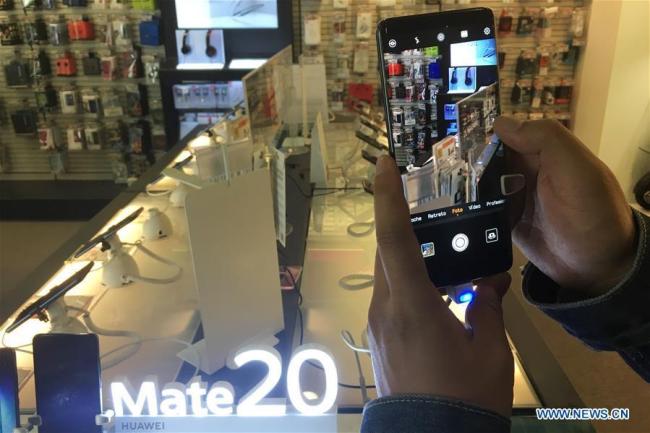 Des gens essaient un smartphone Huawei dans un centre commercial de Barcelone, en Espagne, le 25 novembre 2018.