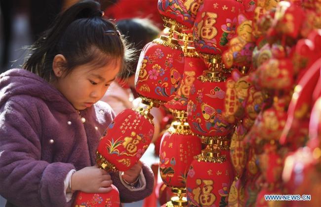 Une enfant regarde des décorations de la fête du Printemps sur un marché de Hefei, capitale de la province de l'Anhui (est de la Chine), le 26 janvier 2019. Des décorations rouges sont actuellement disposées dans toute la Chine pour célébrer le nouvel an lunaire qui tombe le 5 février cette année.