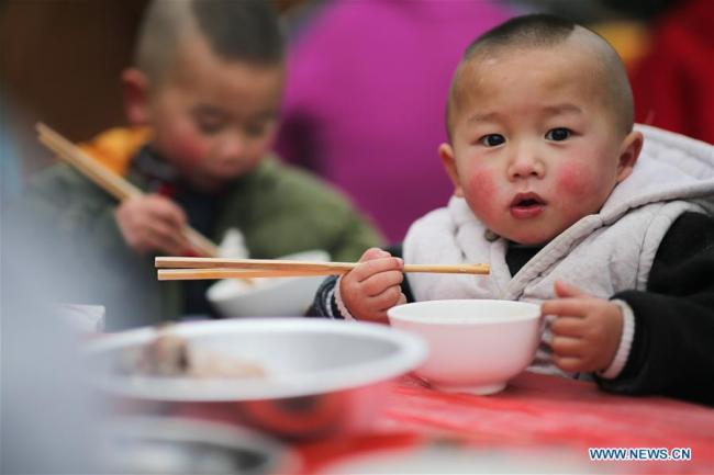  Des enfants d'une communauté de réduction de la pauvreté prennent un repas à l'approche de la fête du Printemps, dans le district de Huishui de la préfecture autonome Buyi et Miao de Qiannan, dans la province chinoise du Guizhou (sud-ouest), le 31 janvier 2019. (Photo : Zhang Hui)