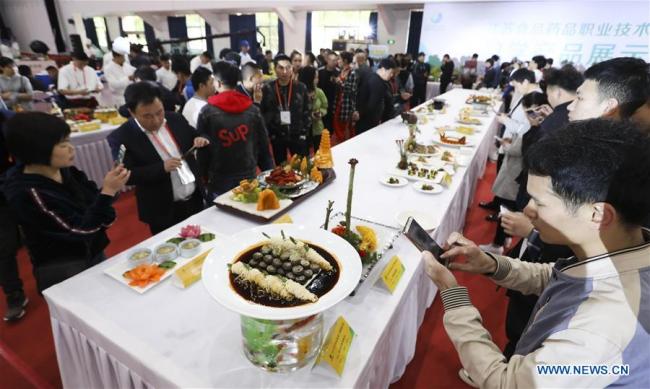 Des visiteurs prennent des photos de plats lors d'un tournoi sur invitation des maîtres de la cuisine de Huaiyang à Huai'an, dans la province chinoise du Jiangsu (est), le 8 mai 2019. (Xinhua/Zhao Qirui)