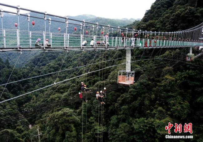 Le 8 août, des amateurs de sport extrême font de la descente en rappel depuis un pont en verre situé à 200 mètres de haut sur le site de Xiatianxia, au xian de Youxi, dans la province du Fujian.