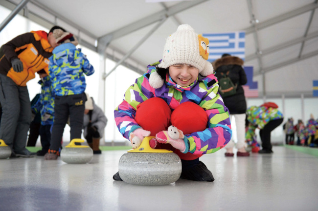 Le 19 janvier 2017, une fille handicapée s'essaye au curling sur une base de sports d'hiver dans la province du Heilongjiang, où la première édition de sports de glace et de neige pour les handicapés en Chine a été lancée. (Photo crédit : Xinhua / Wang Kai)