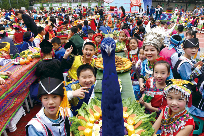 Le 29 mars 2017, les élèves d'une école primaire à Nanning, située dans la région autonome Zhuang du Guangxi, portent des costumes folkloriques traditionnels lors d'un festin célébrant le festival de la chanson Zhuang, qui tombe le troisième jour du troisième mois du calendrier lunaire chinois. (Photo crédit : Xinhua / Zhou Hua)