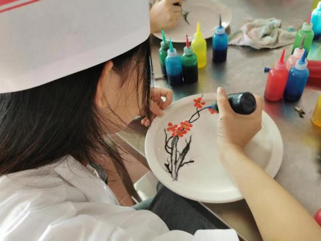 Les apprentis apprennent la technique de peinture sur les plats.