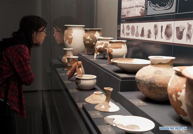 Une visiteuse admire des poteries exposées au musée archéologique d'Erlitou à Luoyang, dans la province chinoise du Henan (centre), le 19 octobre 2019. Le musée, qui a ouvert ses portes samedi à Luoyang, expose plus de 2.000 objets et raconte l'histoire de la dynastie Xia (2070 - 1600 av. J.-C.), la première dynastie connue de la Chine antique. (Photo : Li An)