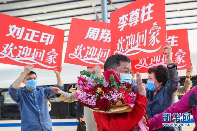 Des médecins et experts du Peking Union Medical College Hospital émus par les fleurs et les applaudissements, le 27 avril, à la Gare de l’Ouest de Beijing.