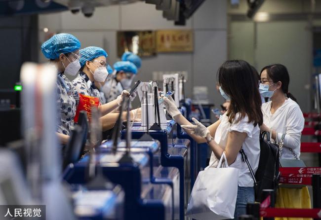 Des passagers montrent aux employés de l’aéroport leurs codes QR de santé verts, le 4 juillet, à l’aéroport international de Beijing-Capitale.