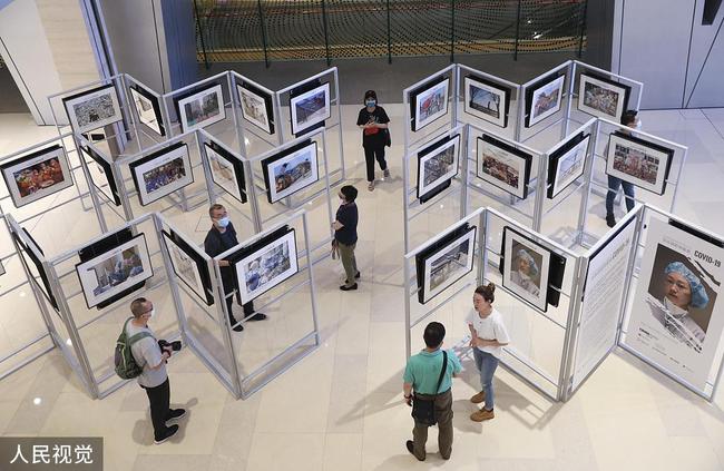 Des gens visitent une exposition intitulée "100 photographes se focalisent sur le COVID-19" et présentant 80 photos prises par les meilleurs photographes chinois pendant la pandémie de COVID-19, au China World Mall, à Beijing, capitale chinoise, le 1er août 2020.