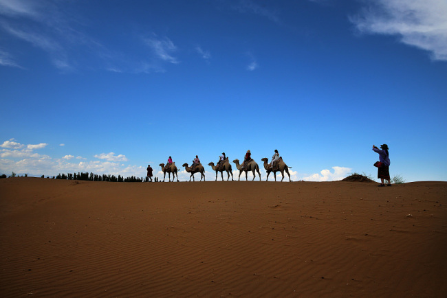 Des touristes visitent la zone touristique du désert de Kumtag à Tourfan, dans la région autonome ouïgoure du Xinjiang (nord-ouest de la Chine). Le désert connaît un flux croissant de touristes.