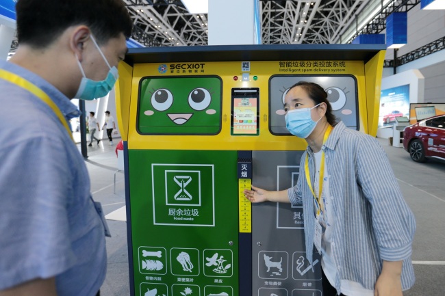 Une employée en train de présenter une poubelle intelligente, le 16 juin, au Salon de l’économie numérique de l’Ouest, à Xi’an.
