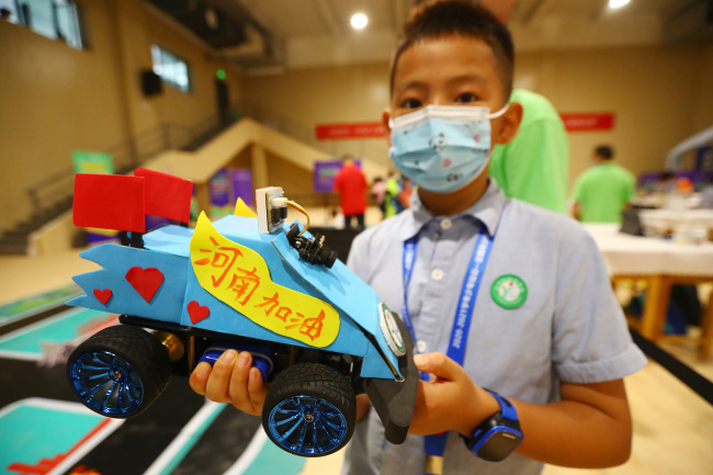 Un élève venant de Chongqing montre son modèle de voiture autonome avec un message pour encourage la lutte contre les innondations dans la province du Henan.