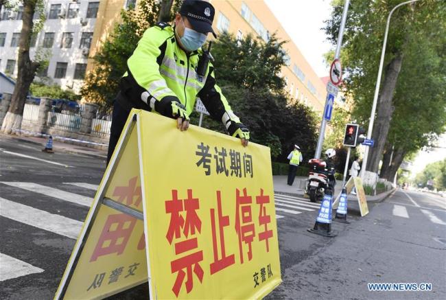 Ένας τροχονόμος τοποθέτει μια προειδοποίηση “Απαγορεύεται η Στάθμευση” έξω από έναν χώρο εξετάσεων σε ένα λύκειο στο Τσανγκτσούν, πρωτεύουσα της επαρχίας Τζιλίν της ΒΑ Κίνας, στις 7 Ιουλίου 2020.(Xinhua / Xu Chang)<br>