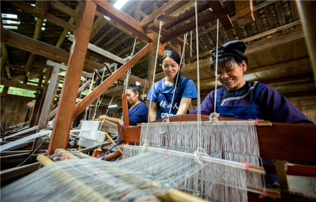 Η Γιανγκ (μεσαία) εργάζεται μαζί με άλλες γυναίκες στην ύφανση των τοπικών υφασμάτων. [Φωτογραφία από τον Fu Jianbin / Για την Κίνα καθημερινά] 