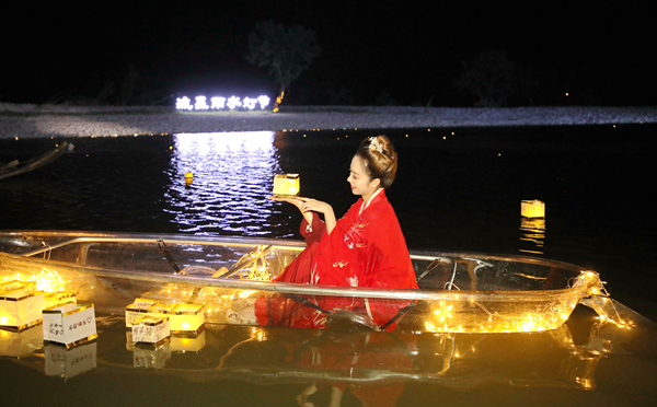 Μια ηθοποιός με αρχαία κινέζικα ρούχα, σε μια παράσταση με μια διαφανή βάρκα για τους τουρίστες στην όχθη του ποταμού του υδροβιότοπου Νανσί του Γιονγκτζιά στην επαρχία Τζετζιάνγκ, το βράδυ της 15 Αυγούστου. [Φωτογραφία / IC]