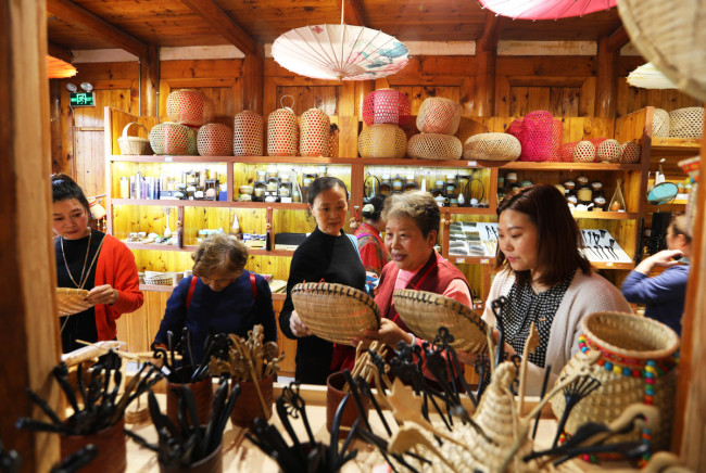 Τουρίστες από το Τσενγκντού αγοράζουν αντικείμενα από μπαμπού σε ένα εργαστήριο στην πόλη Τσισούι της επαρχίας Γκουιτζόου. [Φωτογραφία / Xinhua]