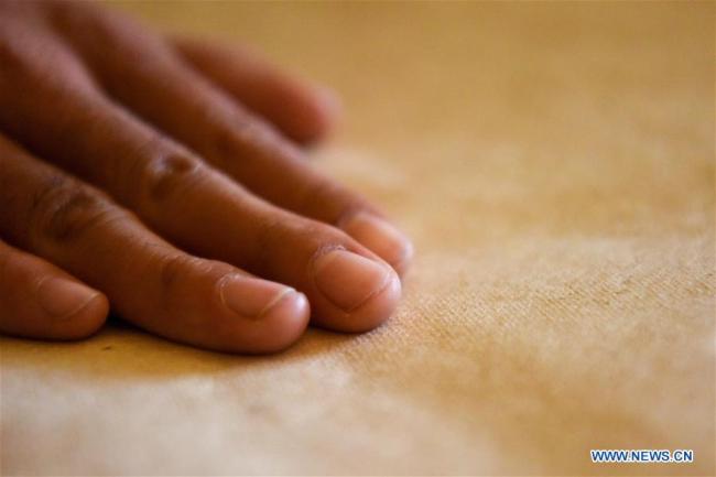 Τεχνίτρια ελέγχει ένα κομμάτι χαρτί από φλοιό μουριάς στην κομητεία Μογιού του Χοτάν, που βρίσκεται στην Αυτόνομη Περιοχή Σιντζιάνγκ Ουιγκούρ της βορειοδυτικής Κίνας, την 1η Νοεμβρίου 2020. 