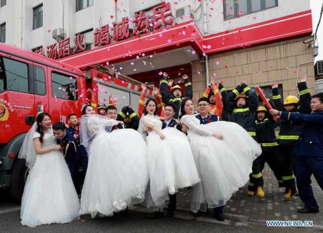 Τα ζευγάρια των νιόπαντρων πυροσβεστών σε γαμήλιες φωτογραφίες μετά τους γάμους τους σε μια ομαδική τελετή που οργανώθηκε στην Πυροσβεστική Υπηρεσία της Σαγκάης στις 4 Ιανουαρίου 2021.