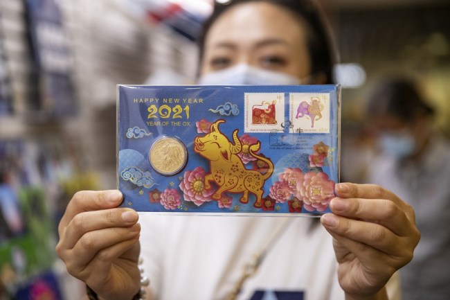 Μια γυναίκα δείχνει τα αναμνηστικά της νομίσματα και γραμματόσημα σε ένα ταχυδρομείο στο Σίδνεϊ της Αυστραλίας, στις 2 Φεβρουαρίου 2021. (Xinhua / Bai Xuefei)