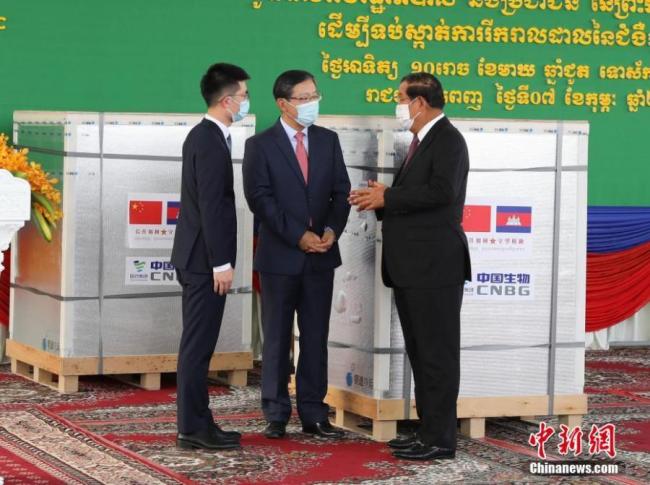 Ο Κινέζος Πρέσβης στην Καμπότζη Γουάνγκ Γουεντιάν, παραδίδει τα εμβόλια της Sinopharm COVID-19 στον Πρωθυπουργό της Καμπότζης Samdech Techo Hun Sen στο Διεθνές Αεροδρόμιο της Πνομ Πεν στην Πνομ Πενχ, Καμπότζη, 7 Φεβρουαρίου 2021. Μια ναυλωμένη πτήση που μετέφερε την πρώτη παρτίδα των εμβολίων Sinopharm COVID-19 που δωρίστηκαν από την Κίνα, καλωσόρισε ο Πρωθυπουργός της Καμπότζης Samdech Techo Hun Sen στο Διεθνές Αεροδρόμιο της Πνομ Πεν. (Φωτογραφία / China News Service)