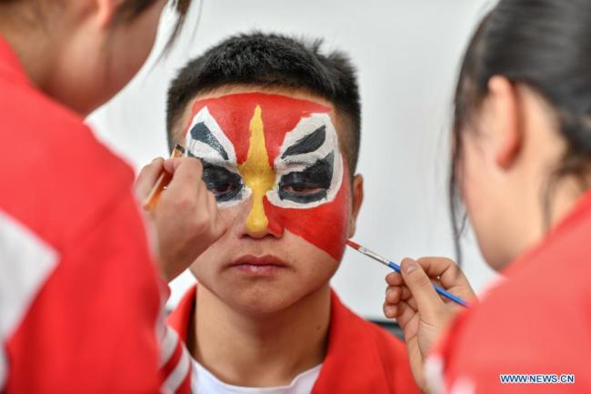 Μαθητές μακιγιάρονται πριν από την πρόβα στο Νο 3 Γυμνάσιο που βρίσκεται στον Αυτόνομο Νομό Τσιενάν Μπουγί και Μιάο που βρισκεται στην νοτιοδυτική Κίνα στις 23 Μαρτίου 2021. <br>