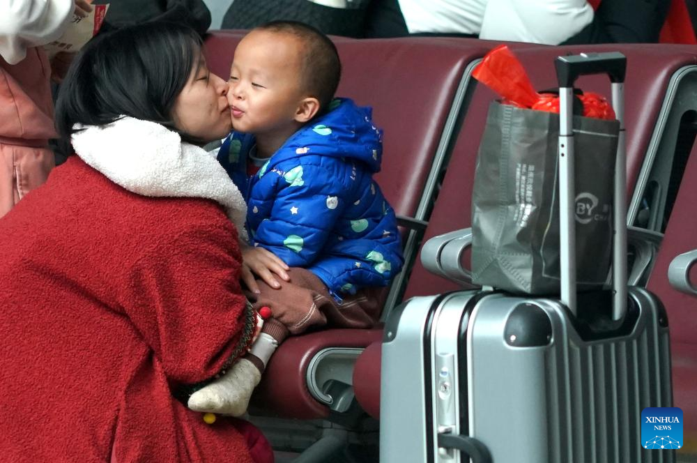Μια γυναίκα φιλάει το παιδί της στην αίθουσα αναμονής του ανατολικού σταθμού του Τζενγκτζόου στην επαρχία Χενάν της κεντρικής Κίνας, 17 Φεβρουαρίου 2024. (Xinhua/Li An)