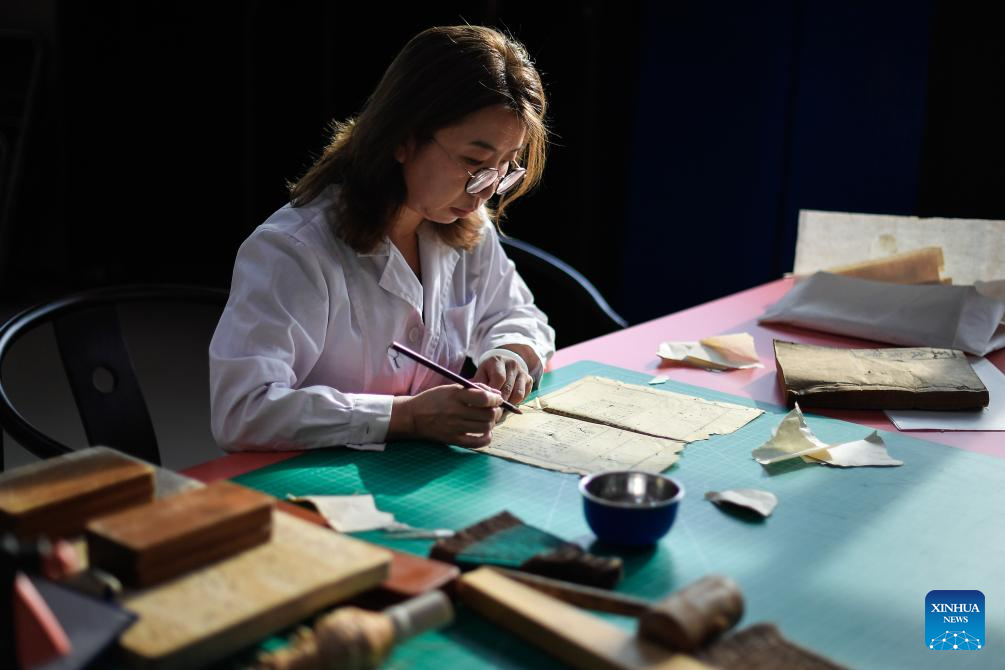Η Τζανγκ Χουά, μια συντηρήτρια αρχαίων βιβλίων στη βιβλιοθήκη του ΠανεπιστημίουΤζιλίν, συντηρεί ένα βιβλίο, στο Τσανγκτσούν, βορειοανατολική επαρχία Τζιλίν της Κίνας, 19 Απριλίου 2024.