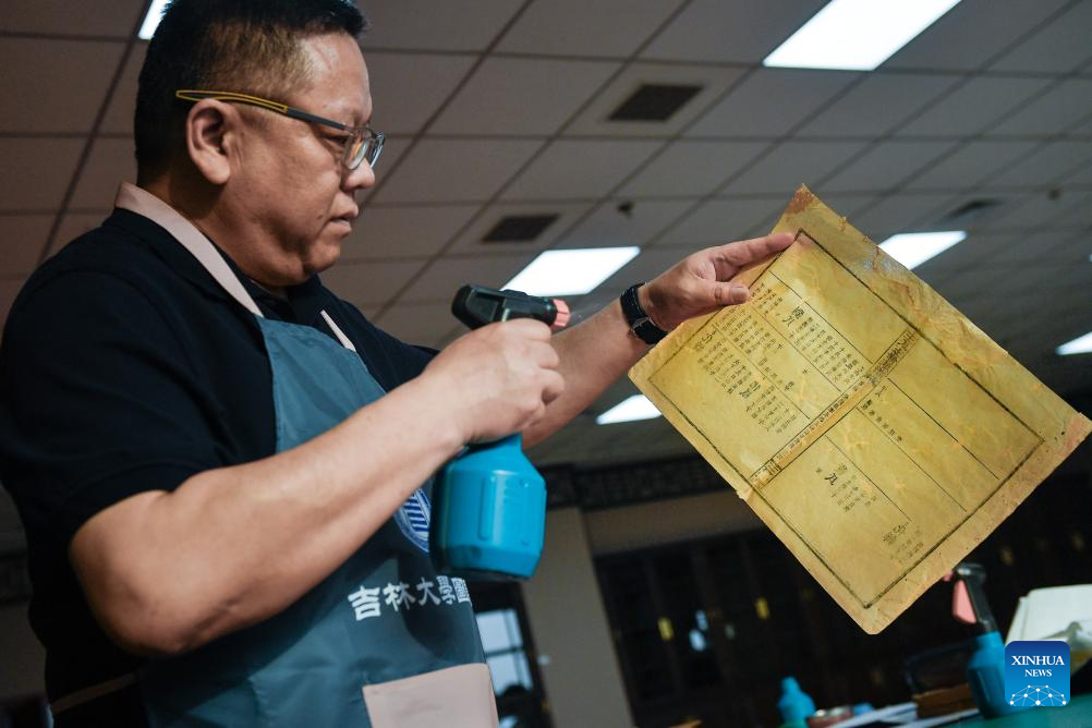 ΟΤζανγκ Τσι, ένας συντηρητής αρχαίων βιβλίων στη βιβλιοθήκη του ΠανεπιστημίουΤζιλίν, ψεκάζει νερό στις αποκατεστημένες σελίδες ενός αρχαίου βιβλίου στη βιβλιοθήκη του Πανεπιστημίου Τζιλίν στο Τσανγκτσούν, βορειοανατολική επαρχία Τζιλίν της Κίνας, 19 Απριλίου 2024. (Xinhua/Xu Chang)