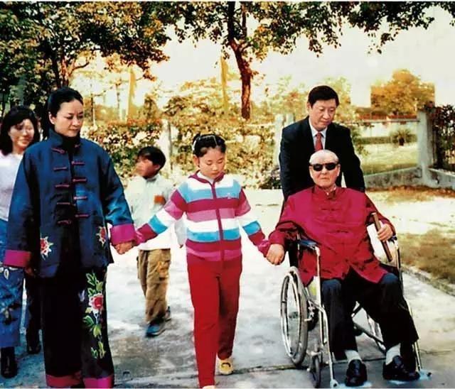 Hszi Csin-ping tolószékben ülő apját, Hszi Csung-hszünt tolva sétál feleségével, Peng Liyuannal és lányával
