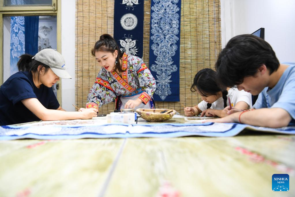 Η Τζουάν – Τζουάν  δείχνει σε συγγενείς και φίλους πώς να ζωγραφίζουν μπατίκ στο Ανσούν της επαρχίας Γκουιτζόου της νοτιοδυτικής Κίνας, 18 Αυγούστου 2022.