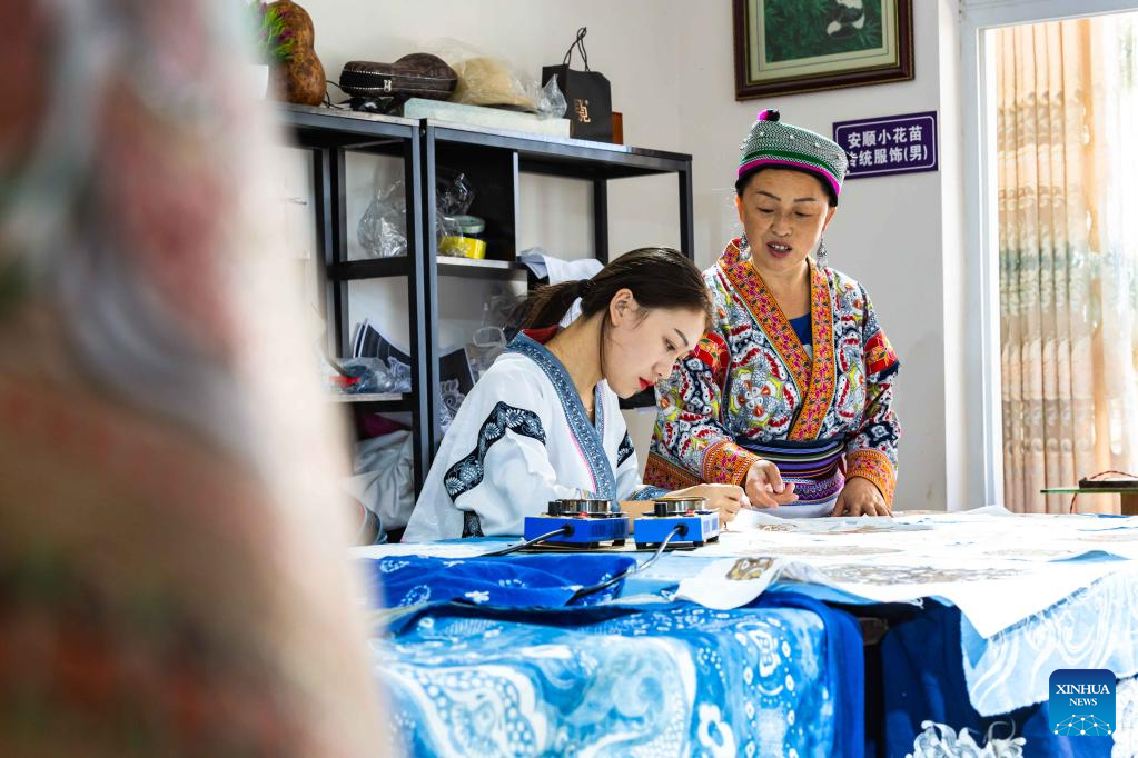 Η μητέρα της  Τζουάν – Τζουάν  της δείχνει πως να κάνει μια ζωγραφιά μπατίκ,  στο Ανσούν της επαρχίας Γκουιτζόου της νοτιοδυτικής Κίνας, 18 Αυγούστου 2022.