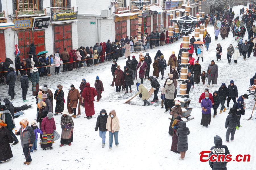 Άνθρωποι περπατούν μέσα στο χιόνι στην οδό Μπαρκχόρ στη Λάσα, στην αυτόνομη περιοχή Σιζάνγκ (Θιβέτ) της νοτιοδυτικής Κίνας, 18 Ιανουαρίου 2024. (Φωτογραφία/China News Service)